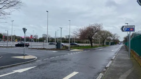 A picture of a road sign saying Ashington station pointing at a carpark