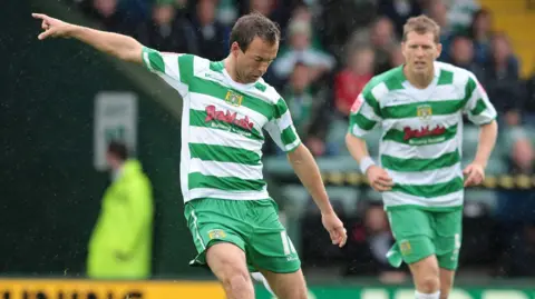Yeovil Town FC Marcus Stewart is on a football pitch playing football in the Yeovil Town kit.