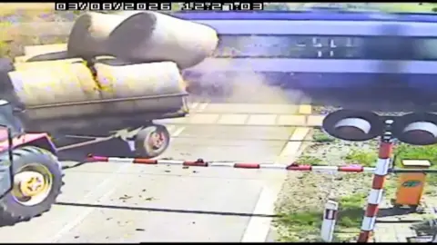 Train crashing into trailer carrying bales of straw