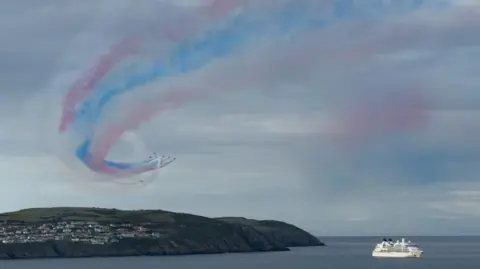 A white cruise ship in the bay with the red arrows above.