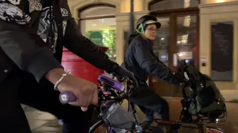 Volunteer bike riders cycle through the streets of London at nighttime 