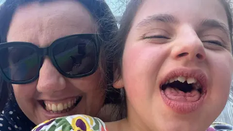 Kirsty A close up of Kirsty with Edith smiling at the camera. Kirsty is wearing shades.