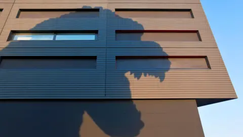 Getty Images The distinctive shadow - including the teeth - of a life-size Godzilla head on a building in Tokyo, Japan.