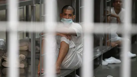 Man behind bars in white jumpsuit