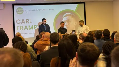 Paul Doherty, Carl Frampton and Ciaran Toman are seen speaking in front of a crowd at the opening of the new centre