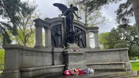 Wreaths laid in front of the Titanic Engineers' Memorial in East Park the memorial has an angel stood tall in the centre and she is flanked by workers.