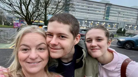 Cerys Lock Cerys, Charlie and Judy at the University Hospital of Wales, Cardiff. They are smiling at the camera. 