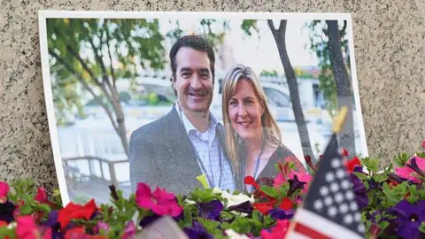 Flowers are shown surrounding a printed image of Melissa Hortman and her husband, Mark. 