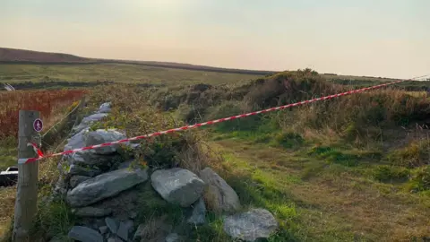 Red and white tape blocks off a footpath