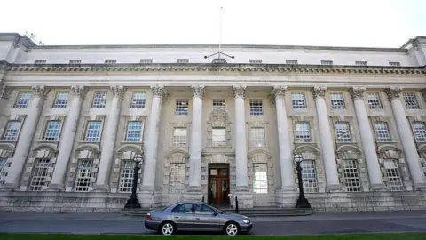 A wide shot of the Royal Courts of Justice in Belfast - a portland stone building of four storeys with a series of pillars and windows