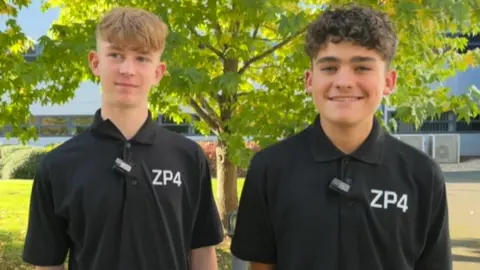 Lewis and Fred stand side by side, smiling at the camera. They wear black polo shirts with ZP4 lettering.