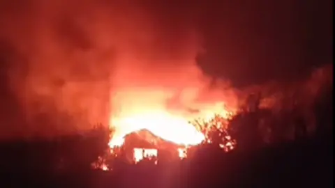 Jersey Fire and Rescue Service A building on fire at night with large flames.