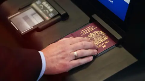 Close up of a person's hand wearing a wedding ring holding down a British passport on a scanner during a demonstration of the new system in September at the Eurostar terminal in Folkestone.