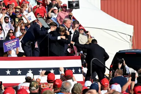 Getty Images Former US President Donald Trump is surrounded by Secret Service agents during a campaign event at Butler Farm Show Inc. in Butler, Pennsylvania, US, on Saturday, July 13, 2024. 