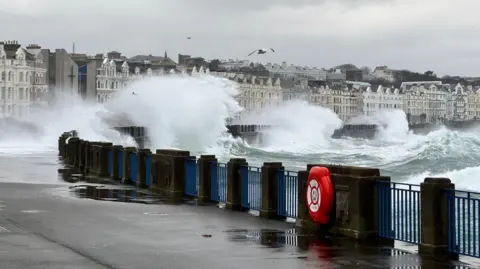 Waves crashing onto the promenade walkway in Douglas.