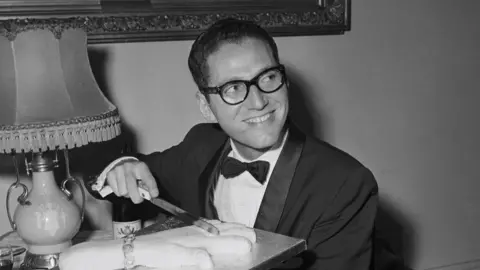 Tom Lehrer pictured cutting a cake in 1959