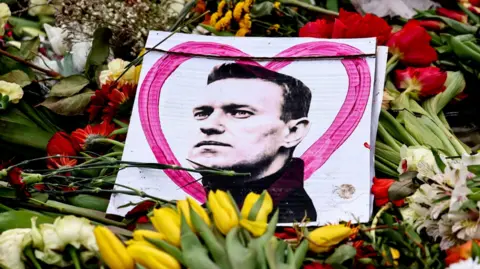 EPA A portrait of late Russian opposition leader Alexei Navalny sits among floral tributes and a candle outside the Russian embassy in Berlin