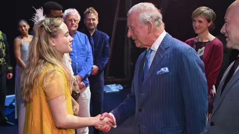 Jeff Spicer via Getty Images King Charles III shakes hands as he meets members of the cast and crew backstage after the Royal Shakespeare Company