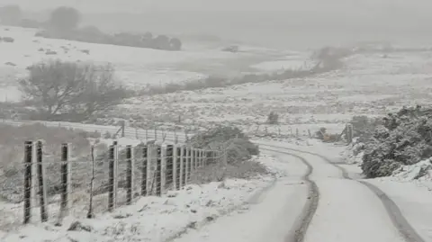 A road near Jamaica Inn set in the moors is covered in snow.