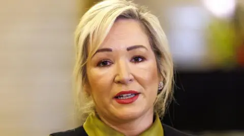 PA Media First Minister Michelle O'Neill, pictured from the shoulders up, with her blonde hair tied up. 