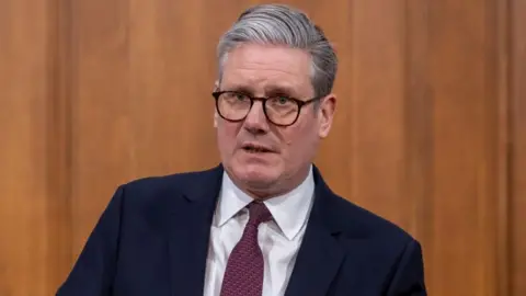 Sir EPA Keir Starmer stands in front of a wooden wall at a London press conference