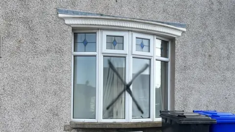 BBC Bay window on a pebble-dashed house that has an X across two of the four panes. 