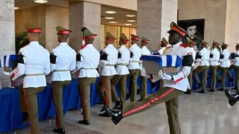 Cuban guards carry the coffins containing the remains of the 32 Cuban soldiers who died