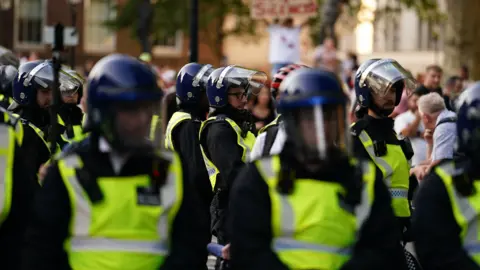 PA Media Police officers look on as people attend the 'Enough is Enough' protest in Whitehall