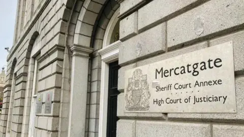 Grey granite building with a black door, and a sign saying 'High Court of Justiciary'