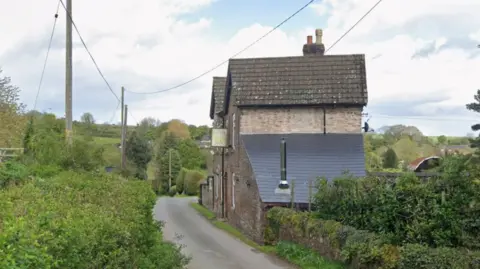 A Google street view image of an old pub building next to a rural road in the middle of the countryside.