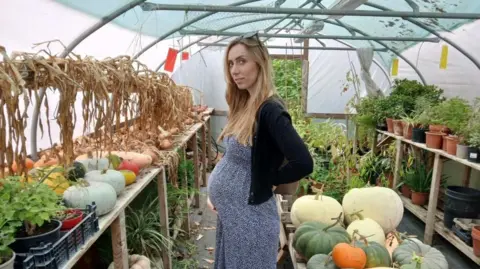 Michaela Ingram-Fuller A pregnant woman in a pumpkin farm.