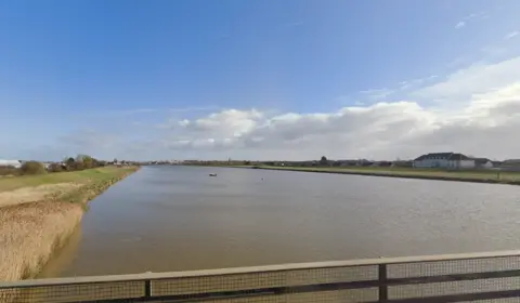 Google Wide shot of the river Great Ouse near King's Lynn, showing expanse of water and buildings in the distance