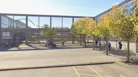 Google A view of a glass fronted school building, with parents and pupils walking around outside