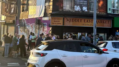 Middle East market on Falls Road with crowd outside