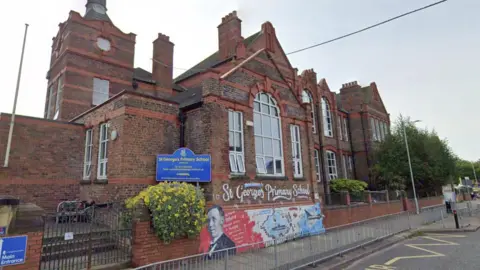 Google St George's Primary School is a brown and red building with large arched windows.