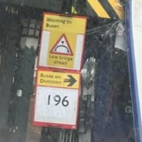 Google A blurred image of a warning sign, saying buses are too tall for the bridge
