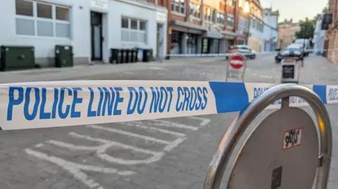 A high street partly cordoned off with police tape