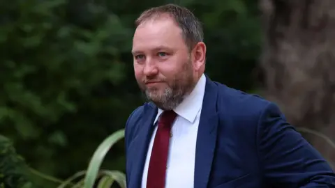 EPA Head and shoulders shot of Ian Murray, a main with short brown hair and a well-trimmed beard with grey patches, walking outside Downing Street. He is looking off to his right with a serious expression on his face. He is wearing a navy suit, white shirt and red tie.