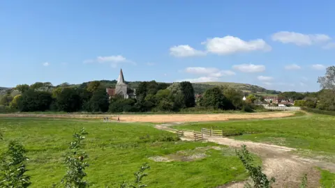 The repaired riverbank just outside Alfriston with the village church in the background