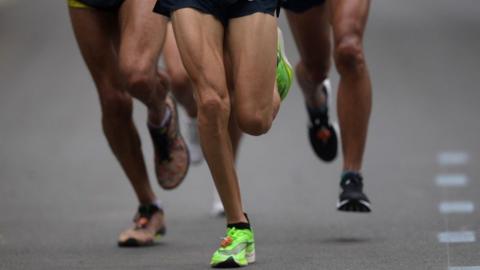 Close up of legs of runners running on a road