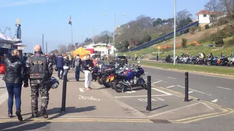 Nick Hull/BBC People walking along Southend seafront, which is lined with motorcycles.