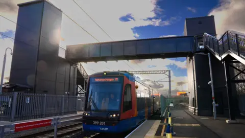A red and blue Supertram is driving on the tracks under a metal pedestrian bridge