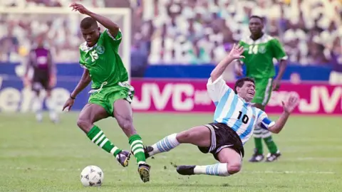 Getty Images Diego Maradona, playing for the Argentina Men's football team against Nigeria in 1994 in mid air falling to the ground following a challenge.