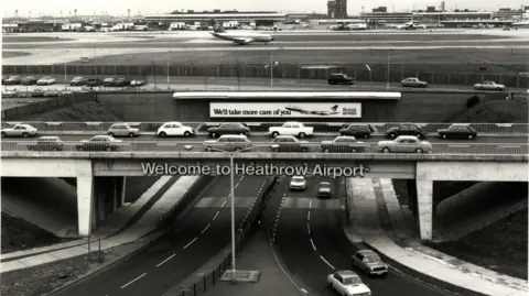 Hillingdon Council Road entrance to Heathrow Airport showing old cars - black and white photo