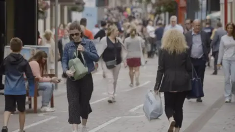 A picture of people walking down a street in Jersey.