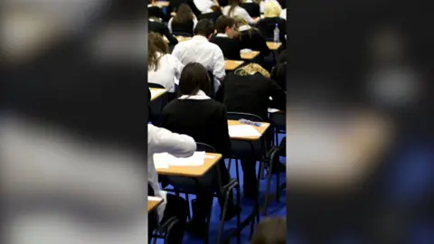 Back view of a row of students taking an exam in a school hall