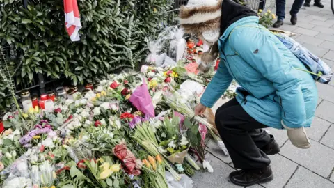 Environmental Protection Agency is a woman who puts a flower at the mourning site after a car was hit in a crowd in Munich, Germany