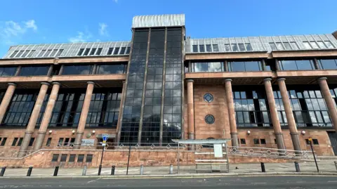 An imposing court building made of red bricks and columns and large black windows.