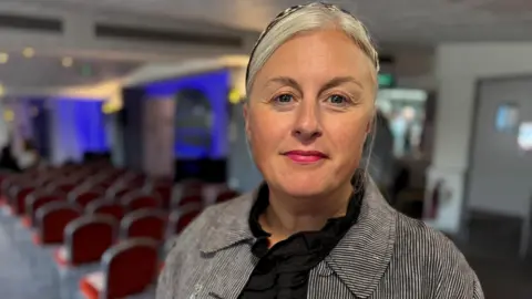 Head and shoulders of Michelle Welsh wearing a striped jacket and black top.