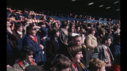 A crowd watching a football match in the stands.